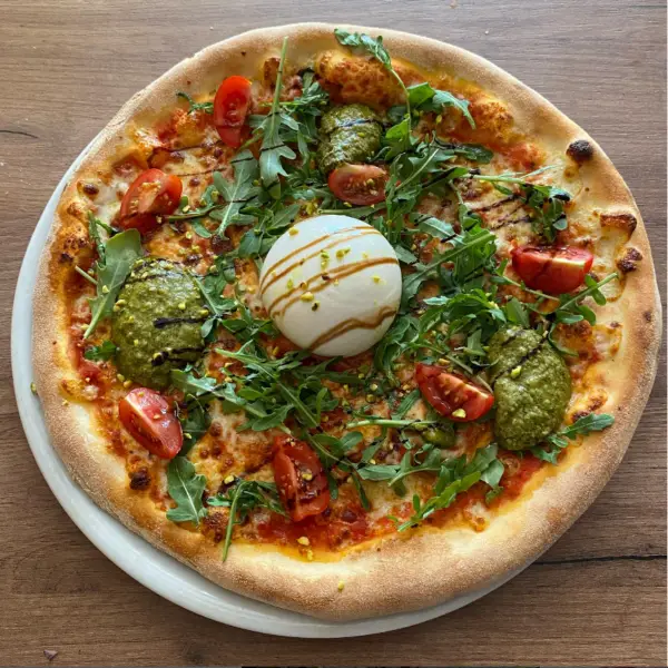 Een pizza Burrata van pizzeria La Rustica Gent, op een houten tafel.